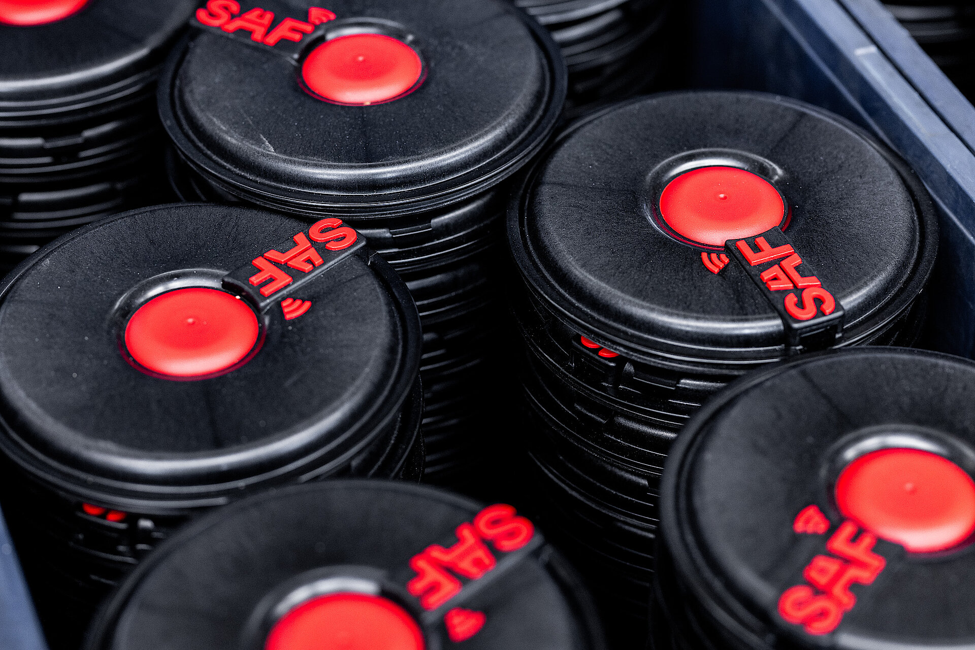 Black SAF hub covers with red logo stacked in a transport crate.
