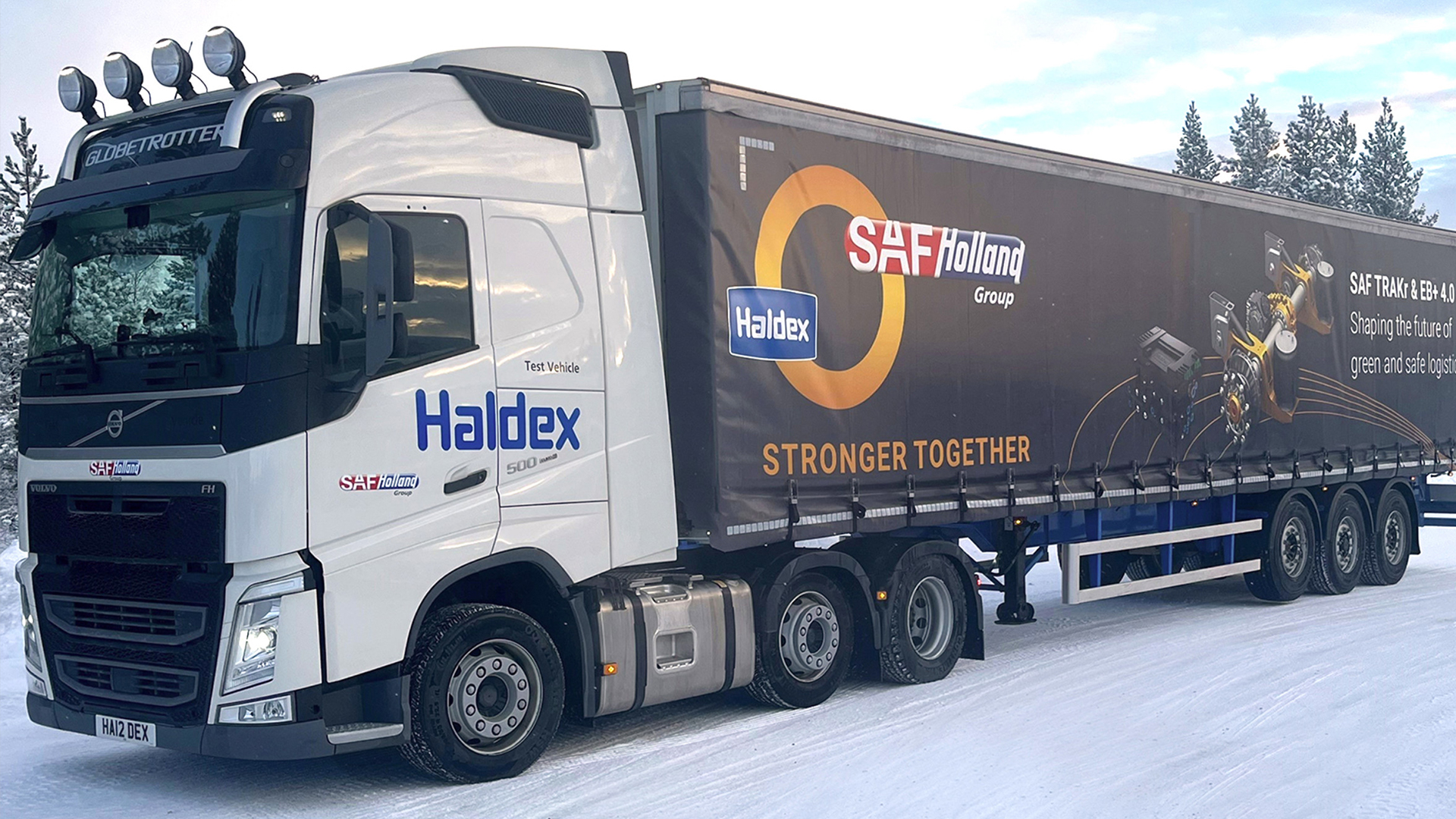 Truck with Haldex branding, towing a SAF-HOLLAND trailer, on a snowy road.